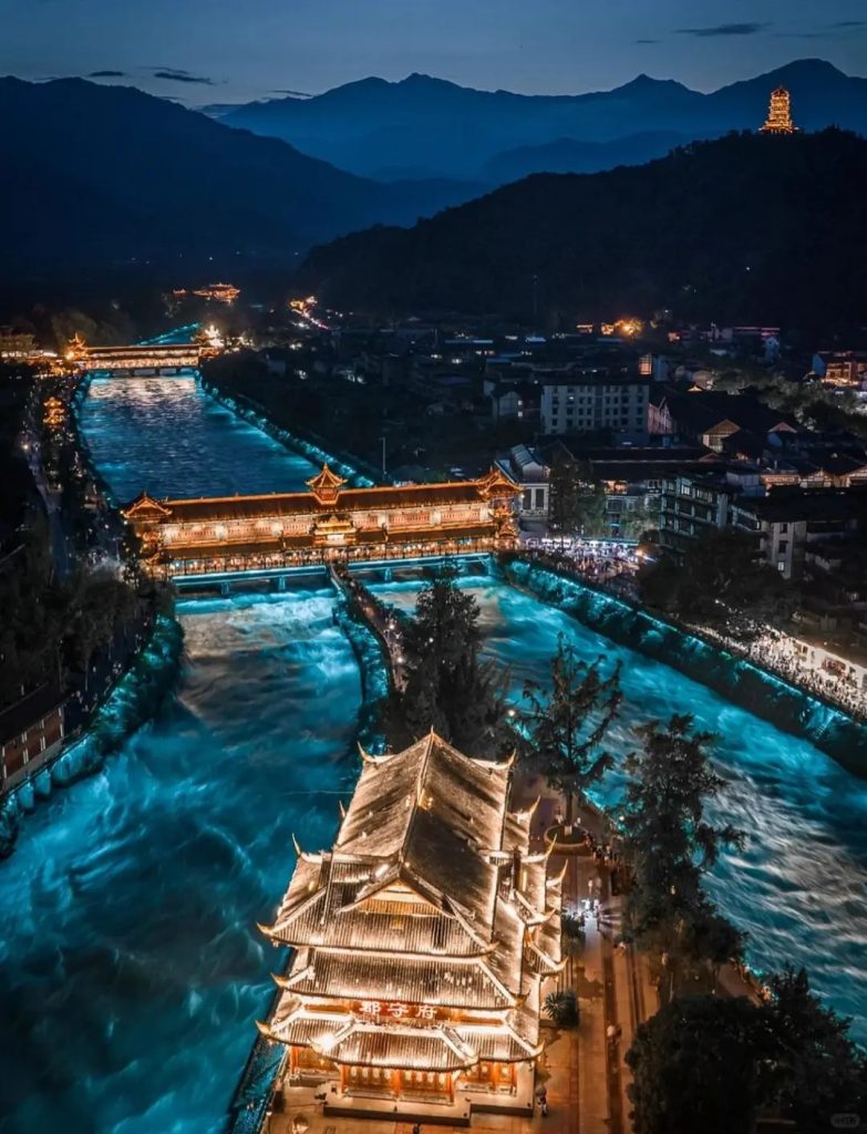 Aerial view of Dujiangyan water system at night, with golden-lit bridges