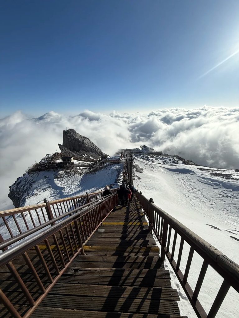 Cable car ascending to Spruce Meadow on Jade Dragon Snow Mountain with snowy peaks in the background