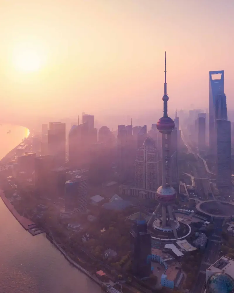 The Oriental Pearl Tower and Pudong skyscrapers beside the Huangpu River in warm light