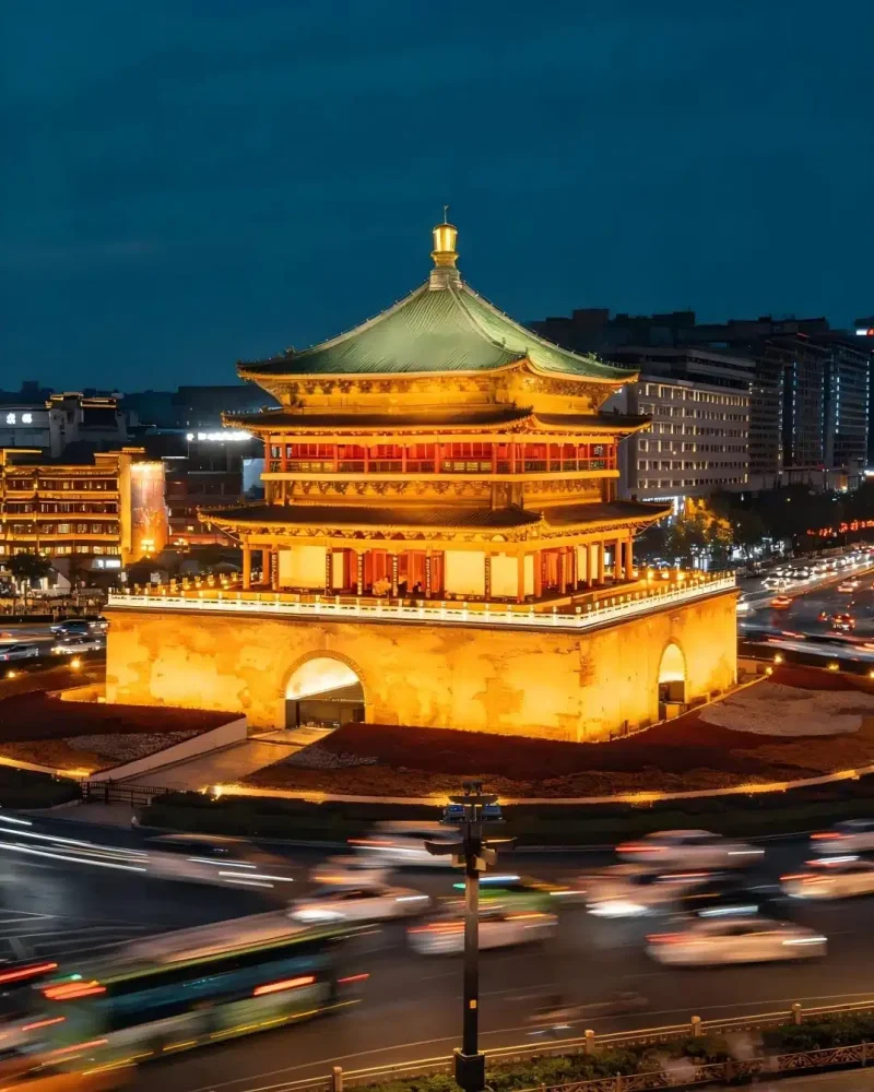 Xi’an Bell Tower illuminated in gold above the surrounding streets at night
