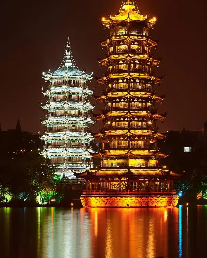 Sun and Moon Pagodas illuminated beside the lake in Guilin