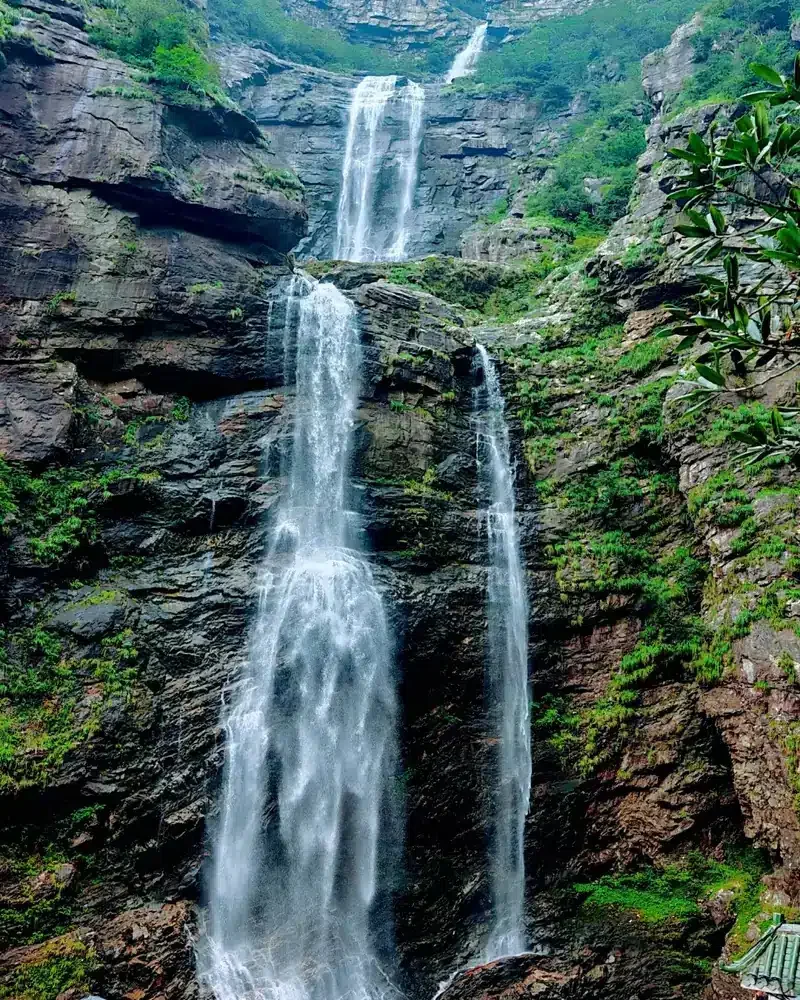 Sandiequan Waterfall descends in three stages over layered rock, surrounded by green vegetation at Lushan.