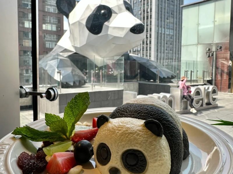 Chengdu IFS Panda Sculpture & Panda Dessert | Taikoo Li Area Panda-shaped dessert on a plate with the Chengdu IFS panda sculpture in the background