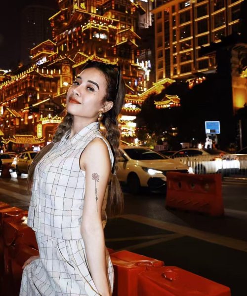 ライトアップされたホンヤ洞窟の前でポーズをとる女性海外旅行者（中国・重慶市