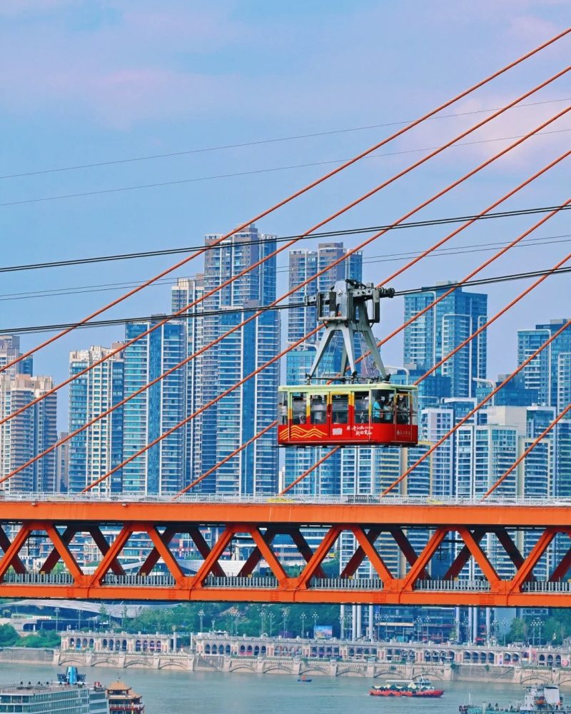Cable car crossing above the river and bridge in Chongqing