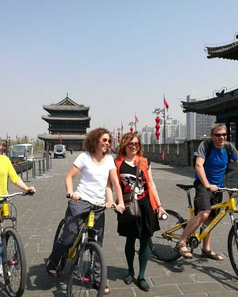The well-preserved fortifications and traditional watchtower of the Ming Dynasty Xi'an City Wall, featuring a wide stone rampart used for cycling tours.