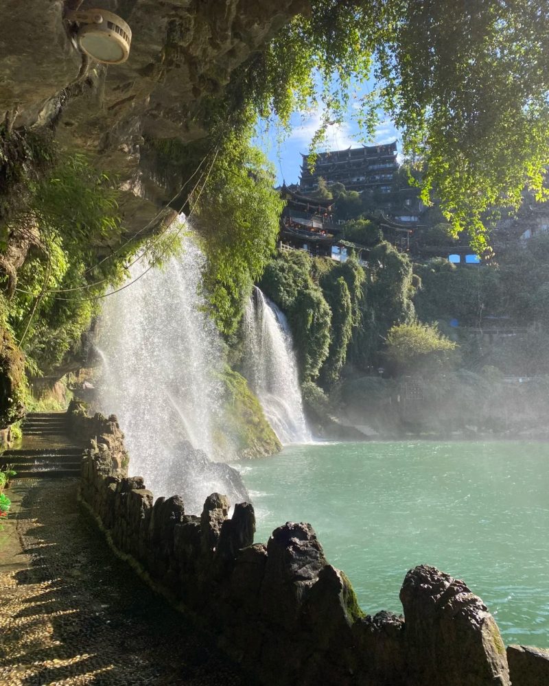 Waterfall and wooden stilt houses in Furong Ancient Town near Zhangjiajie, Hunan, China