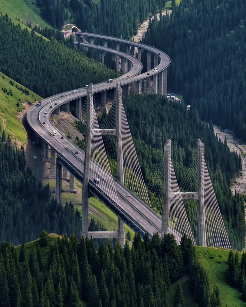Guozigou Bridge winding through the forested Tianshan mountain valley in Ili, Xinjiang