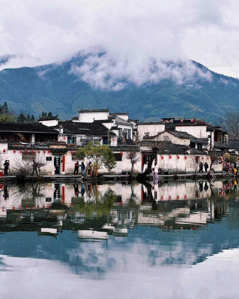 Misty Hongcun ancient village with white-walled Huizhou houses reflected in water, part of the Wangxiangu and East China private tour through Wuyuan and Huangshan.