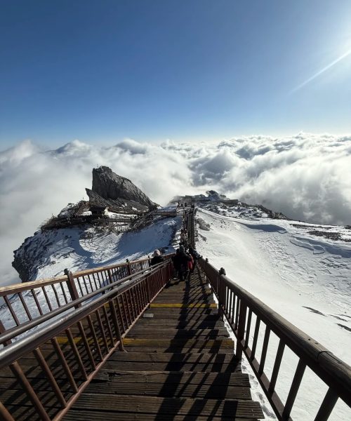 Cable car ascending to Spruce Meadow on Jade Dragon Snow Mountain with snowy peaks in the background
