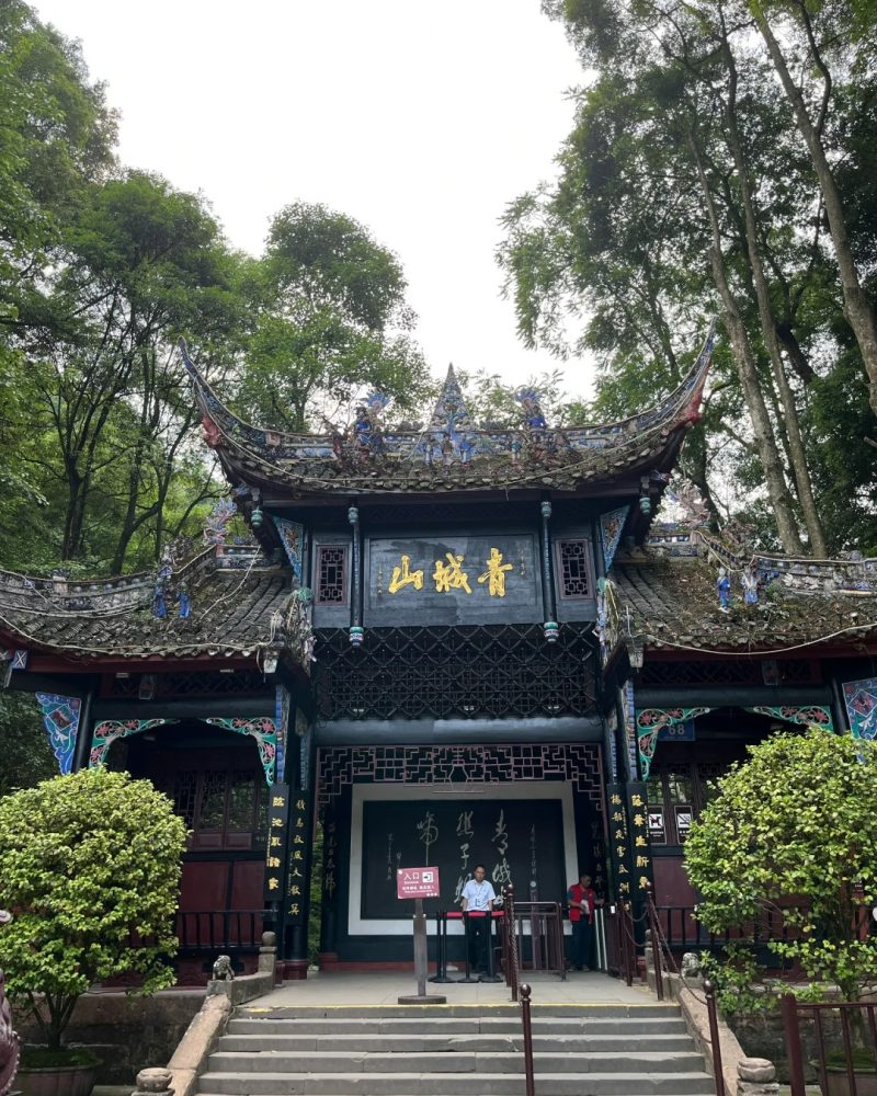 Entrance gate of Mount Qingcheng with the Chinese characters “Qingcheng Mountain” surrounded by trees