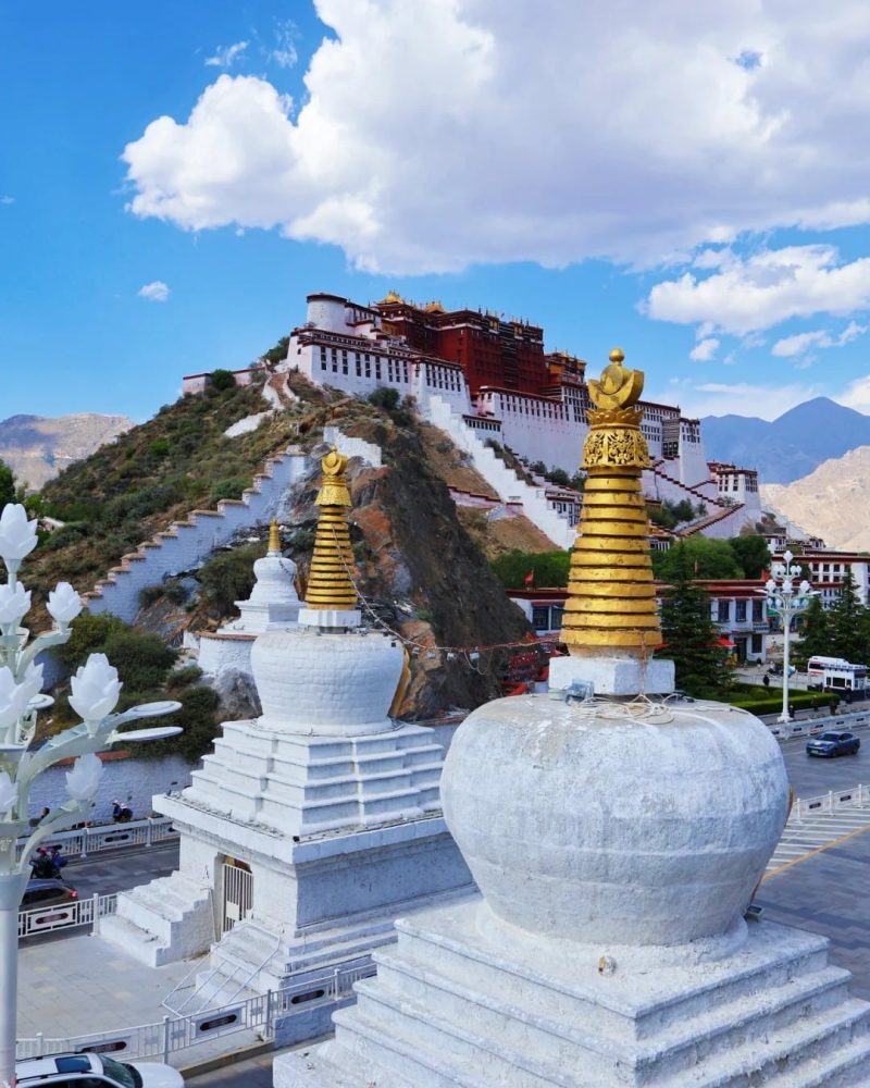 Potala Palace rising above Lhasa with white stupas in the foreground