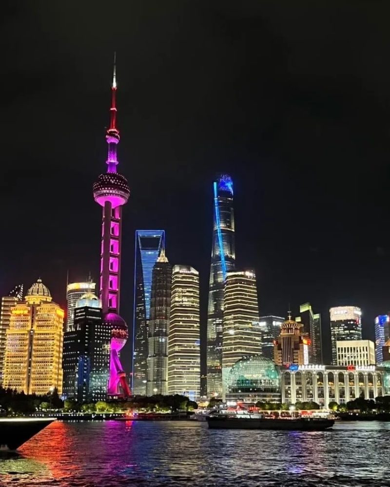 Night view of Shanghai skyline across the Huangpu River from The Bund, featuring the Oriental Pearl Tower