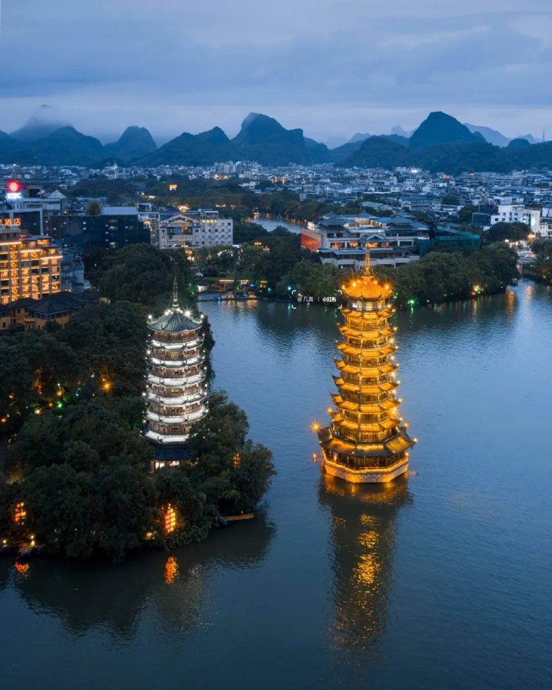 Sun and Moon Twin Pagodas in Guilin, China, illuminated beside the lake at dusk