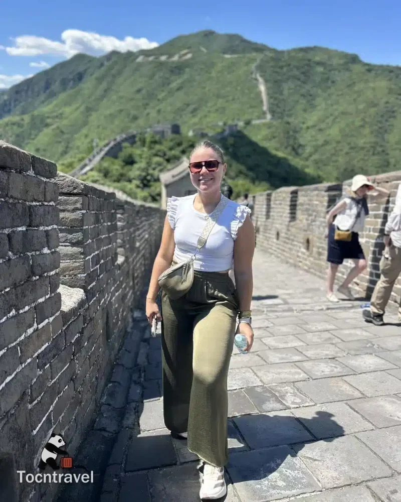 TOCNTRAVEL guest walking along the Mutianyu Great Wall, with green hills behind her