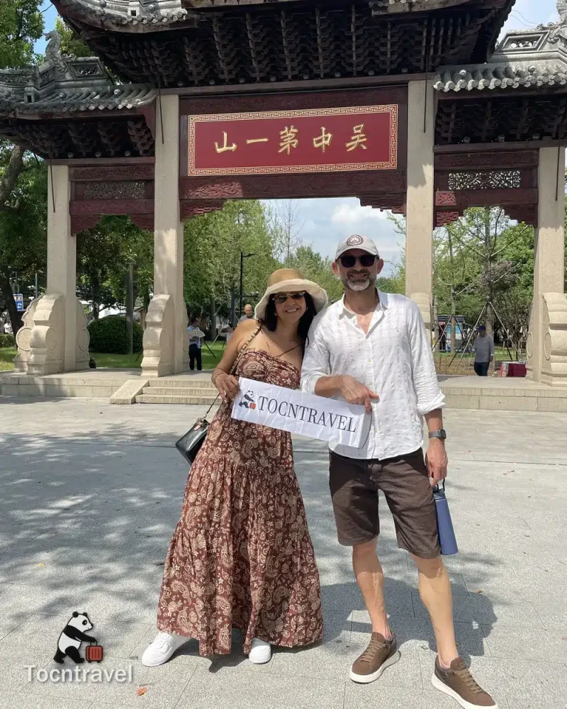 Two TOCNTRAVEL guests beneath the traditional entrance archway at Tiger Hill in Suzhou