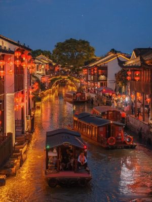 Red lanterns light up traditional houses along Wuzhen’s peaceful canal under a starry sky.