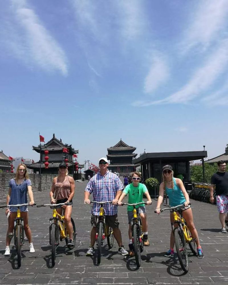 A family biking on the Xi’an City Wall during a private China tour, enjoying the historic views and sunny weather.